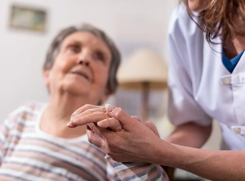 An elderly patient smiling while being assisted by a nurse.